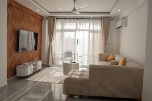 Un salon moderne avec un canapé, un téléviseur et un ventilateur de plafond.