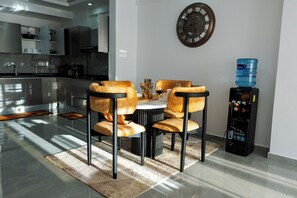 Une cuisine moderne dotée d’appareils électroménagers intégrés, un coin repas avec une table ronde et des chaises, et un distributeur d’eau.