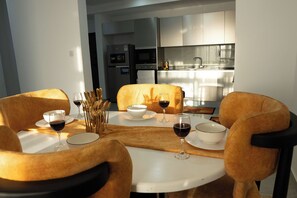 Een eetruimte met een ronde tafel, vier stoelen en een uitzicht op een moderne keuken op de achtergrond.