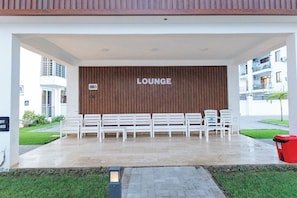Een zithoek met witte banken en een houten wand waarop 'LOUNGE' staat.