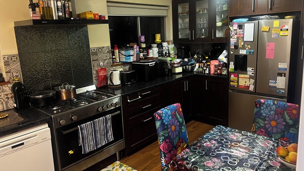 A kitchen with a stove, oven, and refrigerator, with various items on the countertops and cabinets. - Cheap Room in Parafield Gardens (Parafield Gardens)
