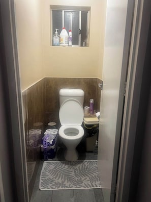 A small bathroom with a toilet, a window above it, and a few toiletries on the windowsill. - Cheap Room in Parafield Gardens (Parafield Gardens)