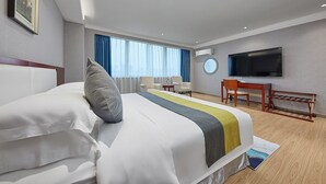Une chambre d’hôtel avec un lit, un bureau, une télévision et une fenêtre avec des rideaux.