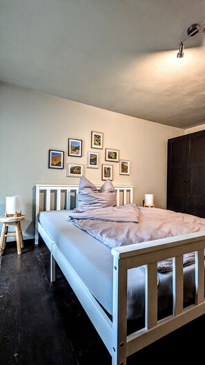 Une chambre à coucher avec un lit, des lampes de chevet, un petit tabouret et une armoire.