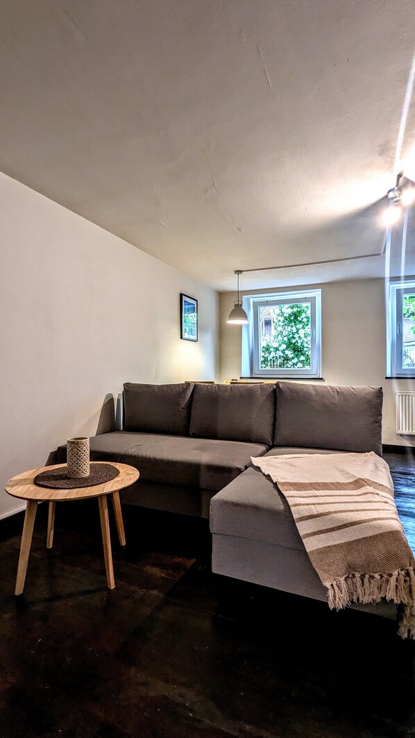 Un salon avec un canapé, une petite table ronde et une fenêtre donnant sur un paysage verdoyant.