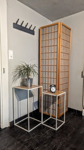 A corner room with a wooden partition, a small table with a clock, and a potted plant. - Apartment "Ferienwohnung am Eichhölzle" with Private Terrace and Wi-Fi (Wehr)
