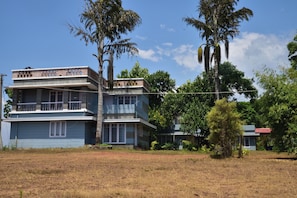 A two-story building with a balcony, surrounded by trees and a clear sky.