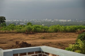 A view of a cityscape with buildings in the distance, a grassy area in the foreground, and a cloudy sky.