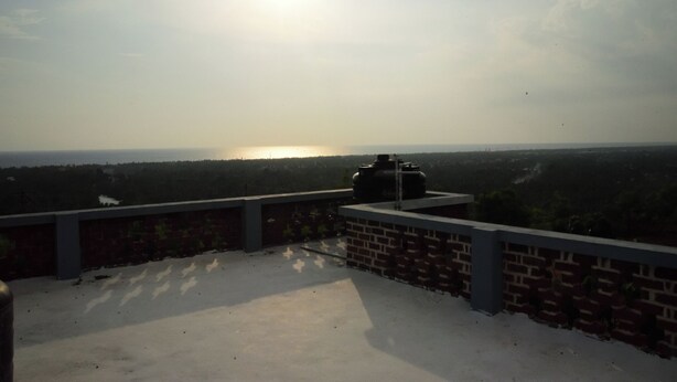 A rooftop terrace with a brick wall, a metal structure, and a view of the horizon.
