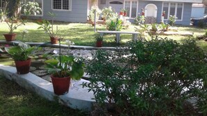 A house with a front yard, potted plants, a bench, and a small pond.