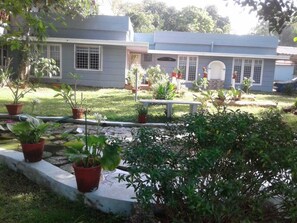 A house with a front yard, potted plants, a bench, and a small pond.