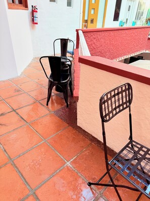 A patio area with tiled flooring, a fire extinguisher mounted on the wall, and two metal chairs. - 2 minutes walk to the boardwalk and 4 to the beach (Puerto Vallarta)