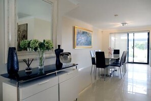 A modern dining area with a glass table, black chairs, and a large mirror on the wall. - Modern Town House (East Fremantle)