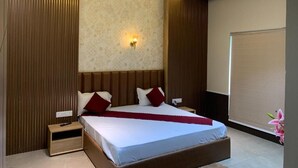Ett modernt hotellrum med en stor säng, träpanel på väggarna, en takfläkt och en väggmonterad lampa.