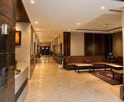 Un vestíbulo de hotel con una recepción, un sofá de cuero marrón, una mesita de centro y plantas en macetas.