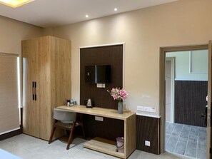 A modern kitchen with a wooden cabinet, a built-in TV, a small dining table, and a vase with flowers. - GRAND VISTA SANGRUR (Sangrur)