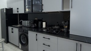 A modern kitchen with a washing machine, a stove, and a coffee maker.