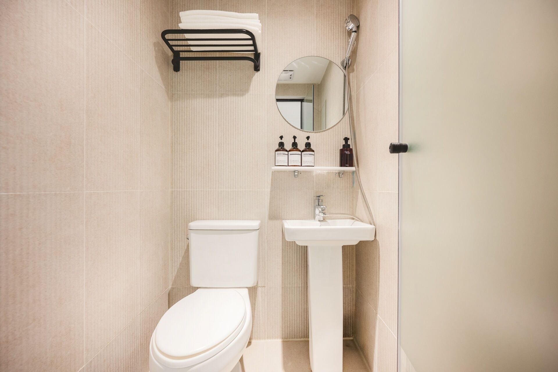 A bathroom with a toilet, sink, towel rack, and a mirror.