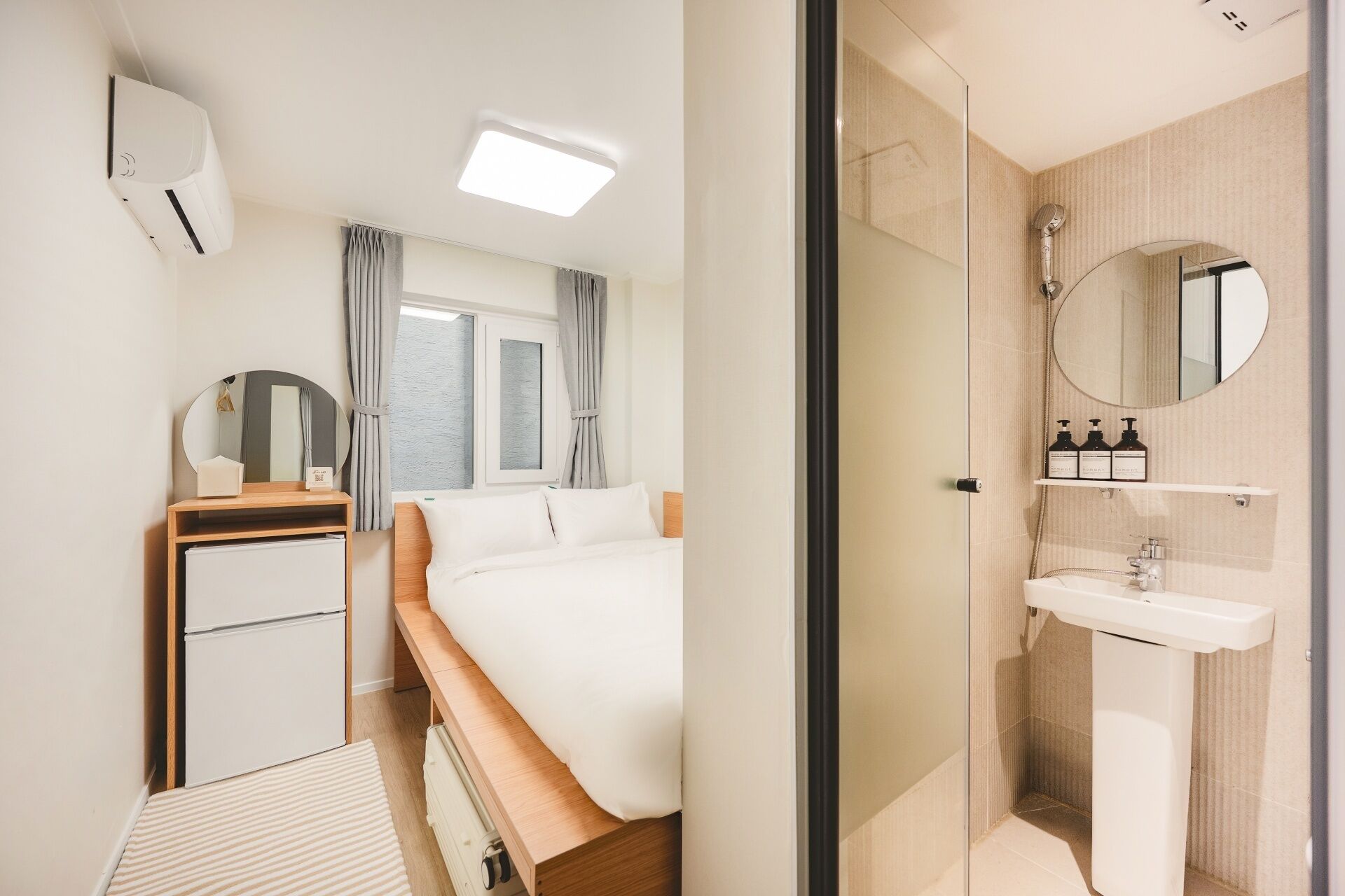 Une chambre d’hôtel comprenant un lit, une table de chevet, un miroir et une salle de bain avec un lavabo et une douche.