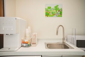 A kitchen with a coffee machine, a sink, and a glass jar with utensils. - EASY STAY in Sinchon Hongdae (Seoul)