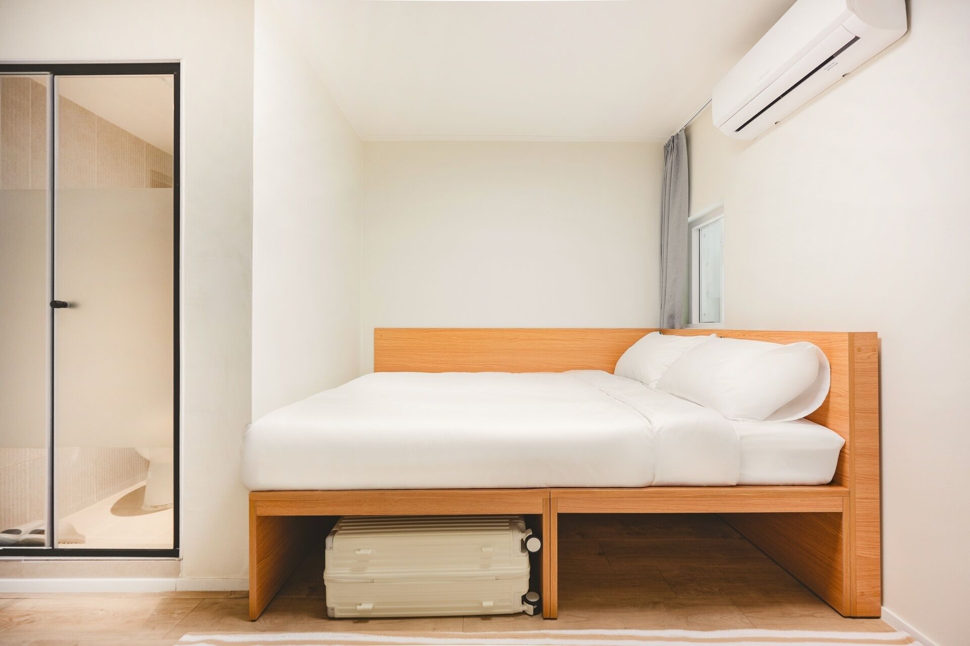 Ein Schlafzimmer mit einem Holzbettrahmen, weißer Bettwäsche, einem Heizkörper unter dem Bett und einer Schiebetür.