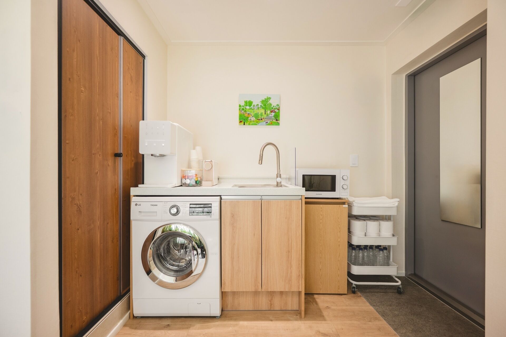 Una cocina compacta equipada con lavadora, microondas y un lavamanos pequeño.