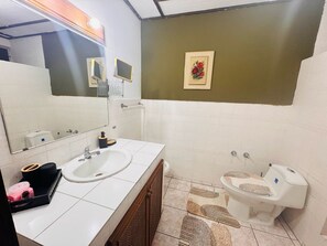 Et badeværelse med to håndvaske, toilet, et spejl og et lille billede i ramme på væggen.