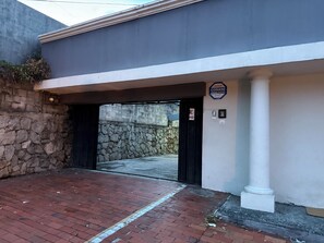 En bygningseingang med en stenvæg, et sort jernhegn og et skilt, der angiver sikkerhedsservice.