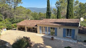 Una casa con tetto in tegole, portico coperto e vialetto in ghiaia.