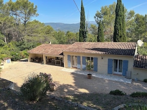 Ein Haus mit Ziegeldach, überdachter Terrasse und einem Schotterweg.