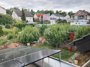 Un quartier résidentiel avec des maisons, un jardin où l’on trouve différentes espèces de plantes, et un ensemble de panneaux solaires.