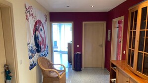 A hallway with a wicker chair, a cabinet, and a door leading to an outdoor area. - Experience the Palatinate, enjoy vineyards with your pet (Gerolsheim)