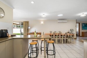 Eine moderne Küche mit Essbereich, Barhocker und Blick ins Freie.