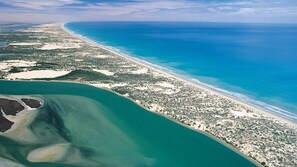 An aerial view of a coastal area with a beach, clear blue waters, and a mix of vegetation and sandy areas. - Banksia Sands - 4 Bedroom Home in Goolwa South (Goolwa South)