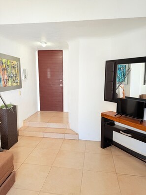 A modern interior with a staircase, a flat-screen TV, and a door. - 2 minutes walk to the boardwalk and 4 to the beach (Puerto Vallarta)