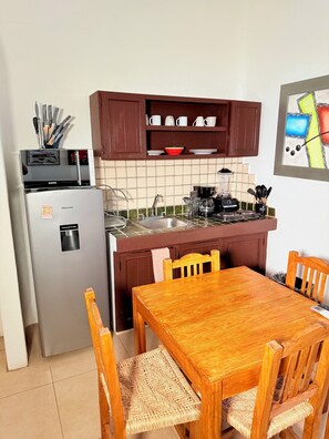 A compact kitchen with a refrigerator, sink, and wooden dining table. - 2 minutes walk to the boardwalk and 4 to the beach (Puerto Vallarta)