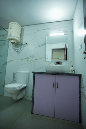 A bathroom with a toilet, sink, cabinet, and a water heater.
