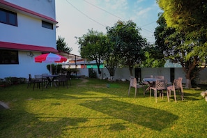 An outdoor seating area with tables and chairs, a red and white umbrella, and a building in the background.