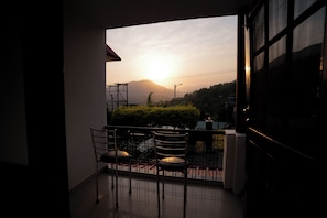 Un balcón con sillas, vista al atardecer y una montaña distante.