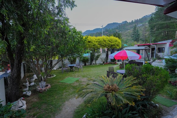 A garden with a patio area, outdoor seating, and a view of a mountain.
