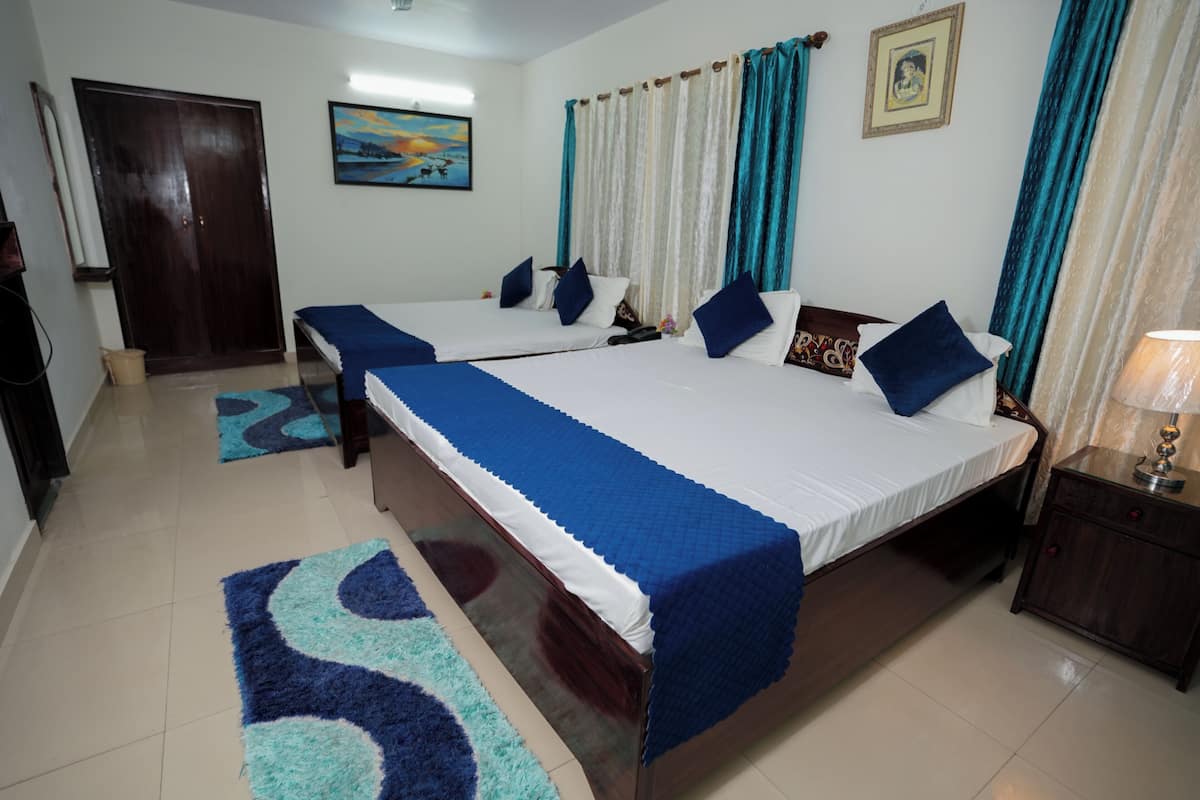 A hotel room with two beds, a wooden wardrobe, a small table, and a nightstand.