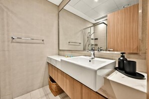 A modern bathroom with a large sink, mirror, and wooden vanity. - Bloomfields 1BR in Azizi Riviera 3  (Dubai)