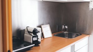 A compact kitchen with a built-in coffee maker, a sink, and white cabinets. - Cosy studio in Hoorn perfect for a relaxing getaway (Hoorn)