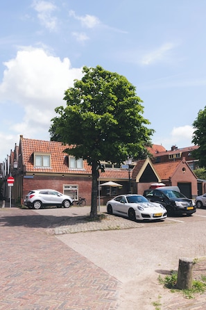 A street scene with a tree, parked cars, and a building with a red-tiled roof. - Cosy studio in Hoorn perfect for a relaxing getaway (Hoorn)
