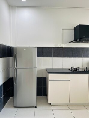 A kitchen with a stainless steel refrigerator, a black microwave, and a gas stove.