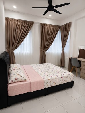 A bedroom with a bed, curtains, a desk, and a ceiling fan.