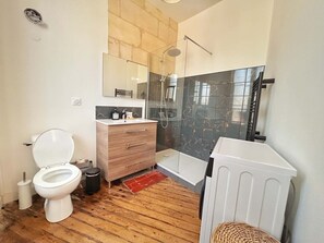 A modern bathroom with a toilet, wooden vanity, glass shower enclosure, and a white radiator. - Vrbo Property (Bordeaux)