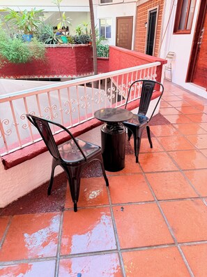 A terrace with two metal chairs and a table, a red wall, and potted plants. - 2 minutes walk to the boardwalk and 4 to the beach (Puerto Vallarta)