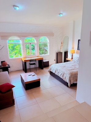 A bedroom with a bed, a desk, and two windows with views of greenery. - 2 minutes walk to the boardwalk and 4 to the beach (Puerto Vallarta)