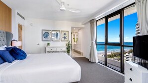 A hotel room with a large bed, a desk, a TV, and a balcony with a view of the ocean. - Surf & Sunrise Beachfront Hideaway by Inn Paradise (Surfers Paradise)